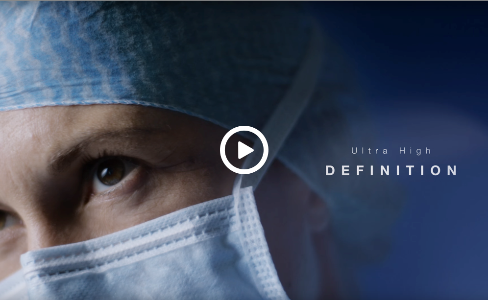 A close-up image of a surgeon's face with an intense focus and overlay text with a video play button for the Ultra High Definition video available on YouTube